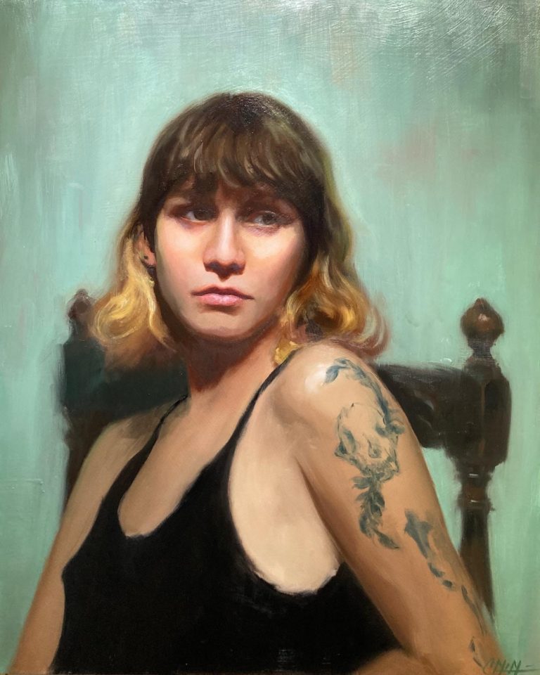 Portrait of Sofia a young woman with a black vest top. She has a tattoo of a dog's skull on her left arm.